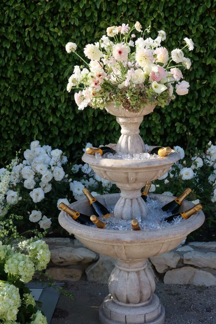 Tiered stone fountain filled with champagne and florals